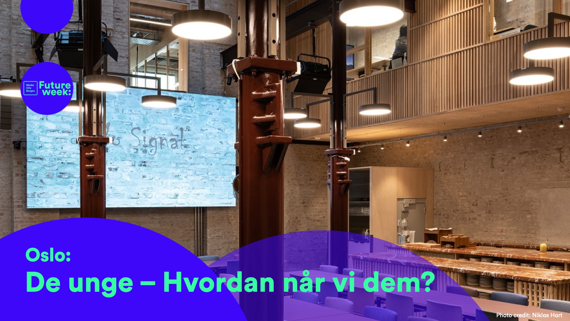 Deler av hovedsalen på Pressens hus, med storskjerm og bjelker. Logo og tekst fra Media City Bergen og FutureWeek, med påskrift "De unge – hvordan når vi dem?"